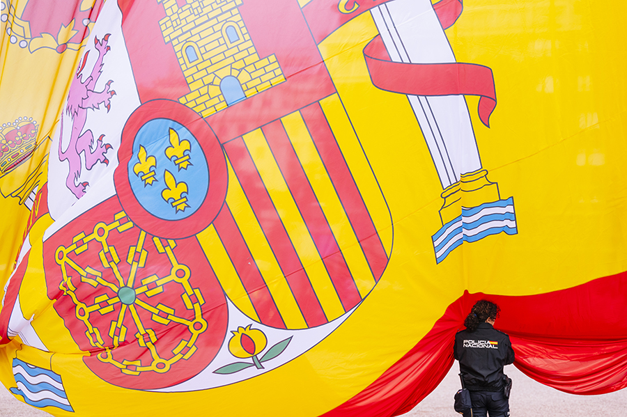Mujer de la Policía Nacional sujetando la bandera de España desplegada.